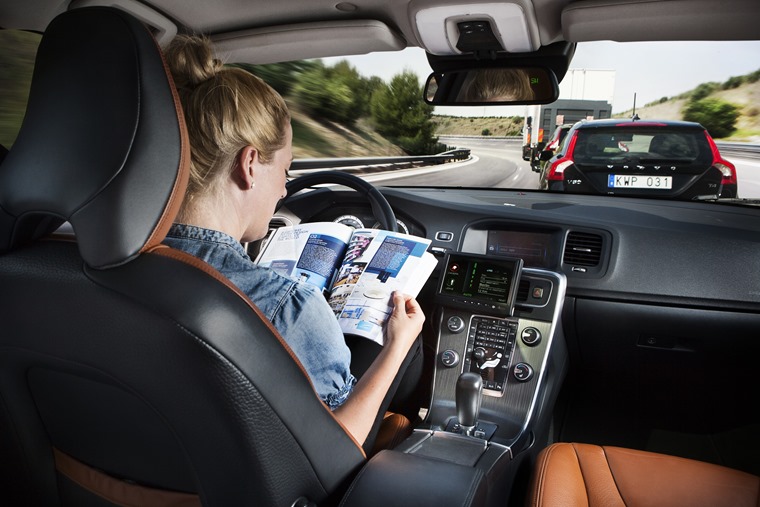 Self driving Volvos - woman in car reading magazine
