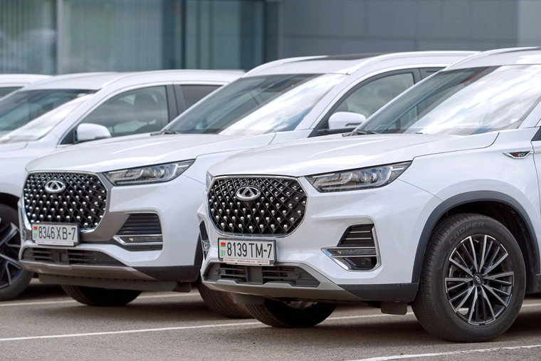 Row of white Chery SUVs parked outside a dealership, highlighting the growing range of Chinese car brands available for leasing in the UK.