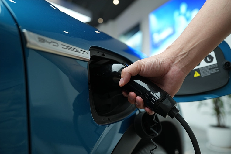 Close-up of an electric vehicle being charged, with a charging cable connected to a blue BYD electric car, highlighting EV technology and sustainable driving.