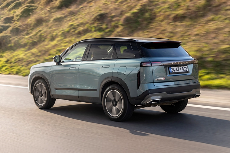 JAECOO 7 SUV driving along a road with a countryside backdrop, representing a modern Chinese car brand expanding into the UK market.