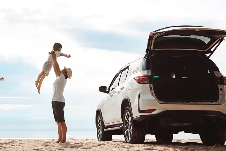 Happy family on a summer road trip at sunset—father, mother, and daughter enjoying a car ride together during their holiday.