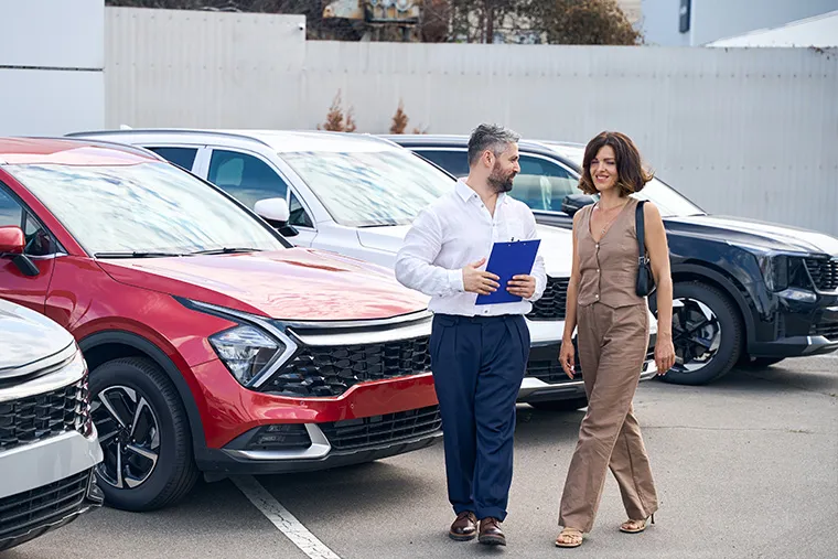Female client talking with salesman manager at car salon showroom outdoors