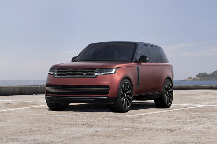 Red Range Rover luxury SUV shown in a studio setting with a black roof and alloy wheels.