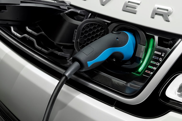 Close-up of a blue-and-black charging connector plugged into a white luxury electric car, conveying a sleek, modern luxury feel.