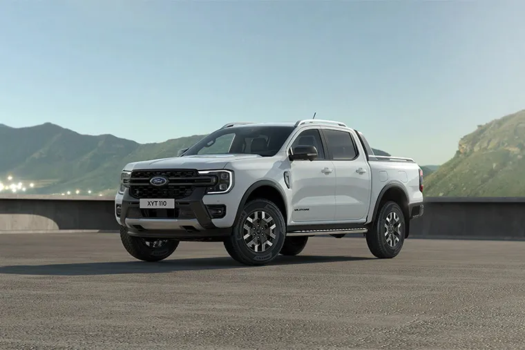 A white Ford Ranger pickup truck parked in front of a mountainous backdrop, showcasing its rugged design and powerful presence. Ideal for businesses in need of a versatile, durable vehicle for leasing, combining strength with modern styling. 