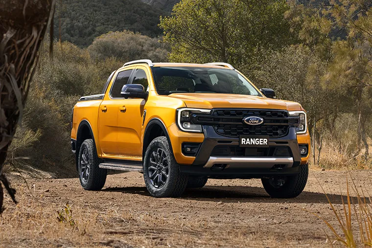 A bright yellow Ford Ranger pickup truck parked in a rugged outdoor setting.