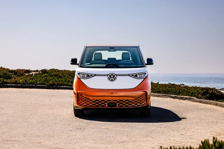 Front view of a Volkswagen electric van, showcasing its modern design with a vibrant orange and white exterior.