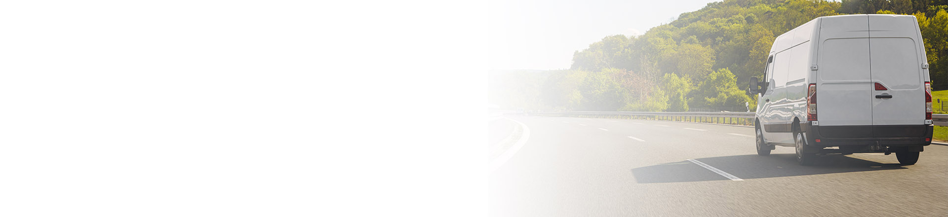 A white van driving along a highway with lush greenery in the background