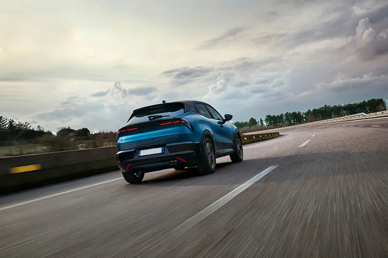 Blue Alfa Romeo Tonale rear view driving on open road