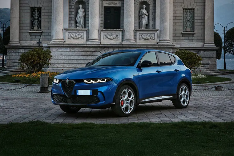 Blue Alfa Romeo Tonale SUV parked in front of historic building