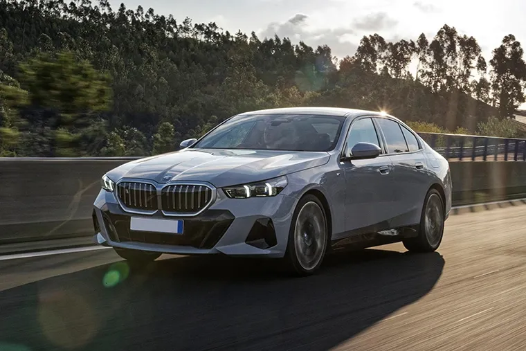 BMW 5 Series saloon driving on a scenic road