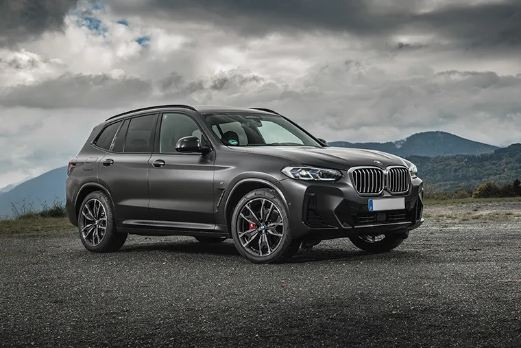 Rear view of the 2025 BMW iX1 electric SUV driving on a mountain road