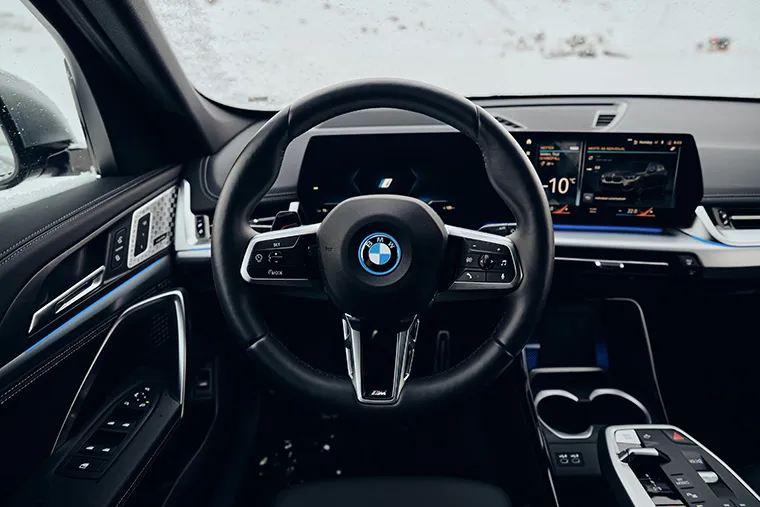 Interior view of a modern BMW featuring a digital dashboard, multifunction steering wheel, and high-tech driver display with ambient lighting.