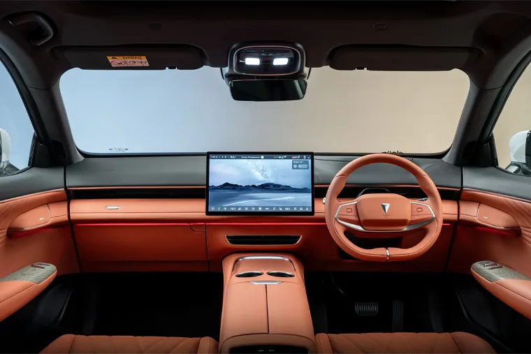 Interior view of a Changan vehicle showing a wide digital dashboard with a large central touchscreen, a modern steering wheel, and a cabin finished in orange leather upholstery with a minimalist, premium design.