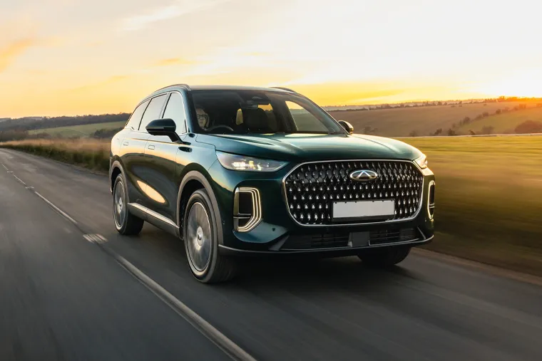 Green Chery SUV driving at sunset through open countryside, featuring a distinctive diamond-pattern front grille and premium LED headlights.