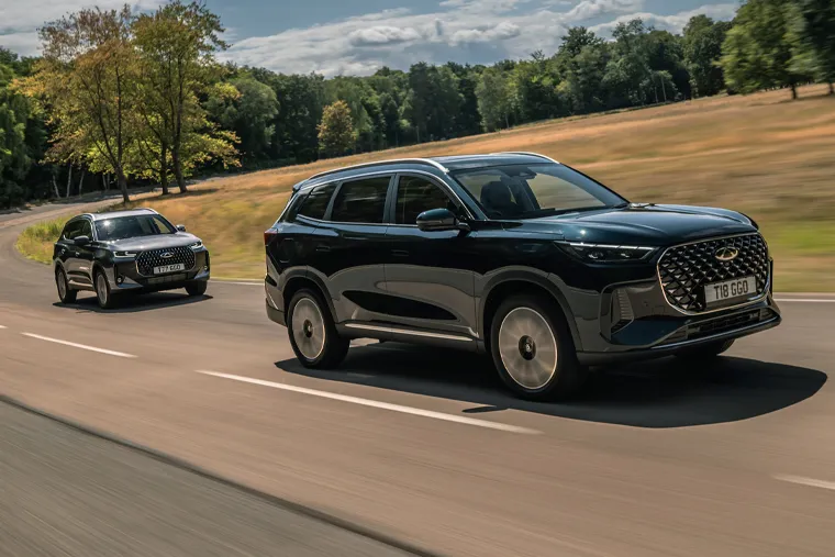 Two Chery SUVs driving on a countryside road, highlighting their bold front grilles, smooth body styling and strong road presence