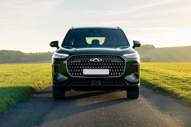 Front-facing view of a Chery SUV on a rural road, highlighting its bold grille design, sharp LED lighting and wide, confident stance.