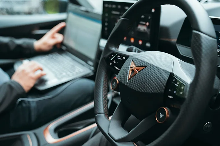 Close-up of Cupra steering wheel with copper badge and stitching, highlighting the sporty and high-tech cabin design.