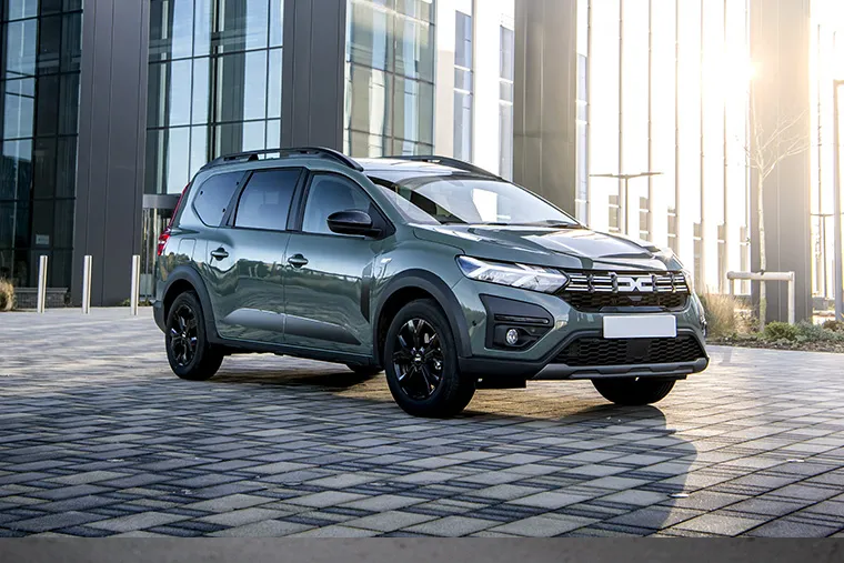 Dacia Jogger parked in front of modern office buildings at sunset