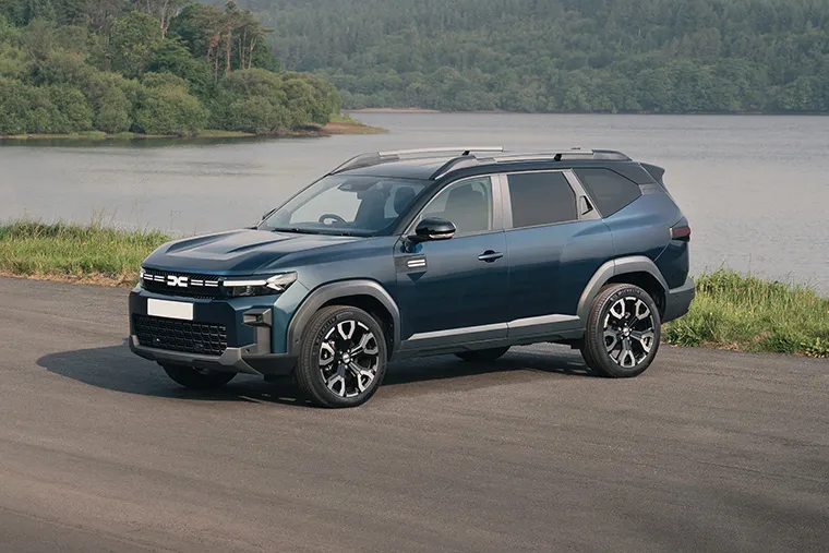 Dacia SUV by a scenic lakeside road surrounded by nature