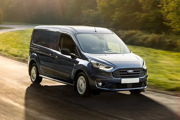 Ford Transit Connect van driving on a country road in sunlight.