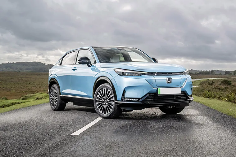 Light blue electric Honda SUV parked on a countryside road under a cloudy sky