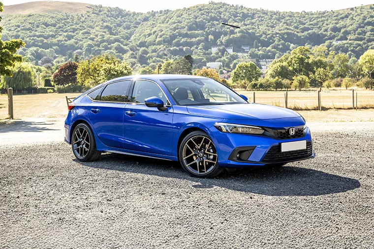 Blue Honda saloon car parked on a gravel road with scenic countryside and hills in the background under a clear sky
