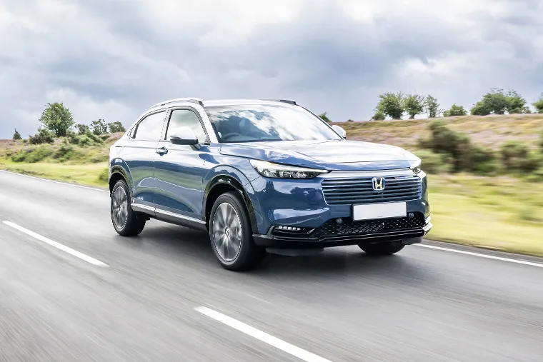 Blue Honda SUV driving on an open country road under a cloudy sky