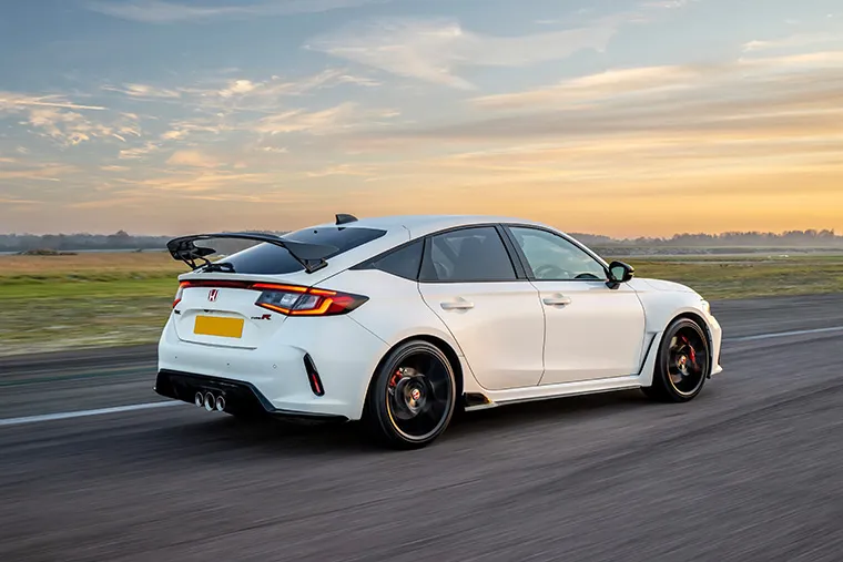 White Honda Civic Type R driving on an open road at sunset with rear spoiler visible