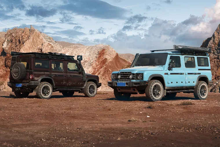 Two INEOS Grenadier off‑road SUVs in rugged desert landscape, showcasing model variations, roof accessories and adventure‑ready 4x4 design.