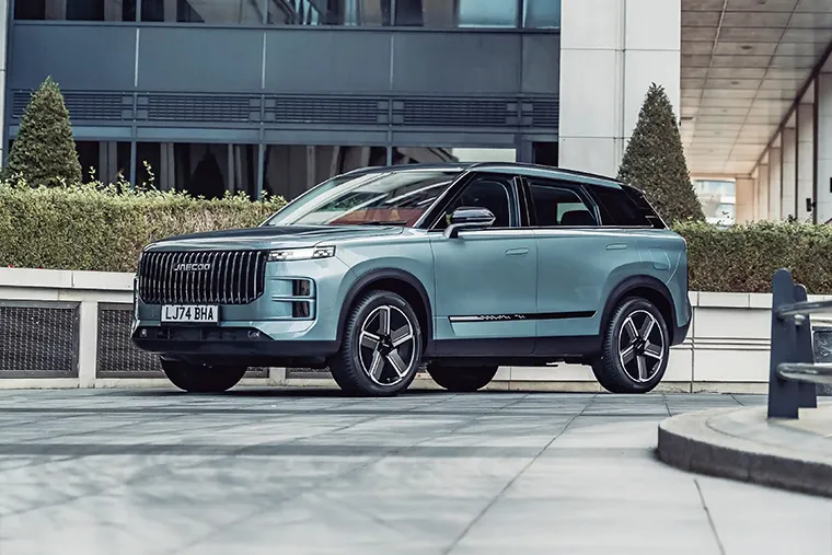 Blue Jaecoo SUV parked in a modern urban setting, showcasing bold grille and sleek design.