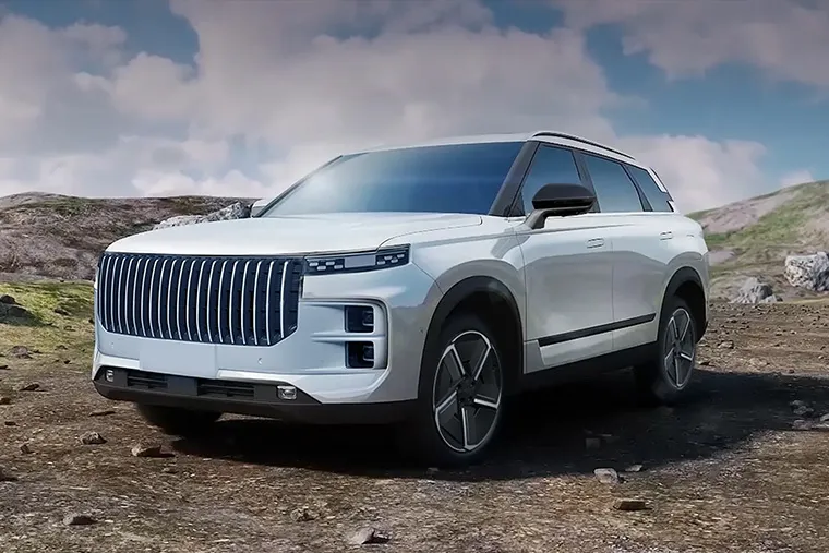 Jaecoo SUV in white with bold vertical grille, parked on rocky terrain under cloudy sky.