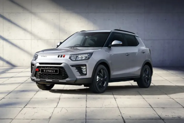Silver KGM Tivoli compact SUV parked in a modern concrete courtyard with angled sunlight and shadows across the floor