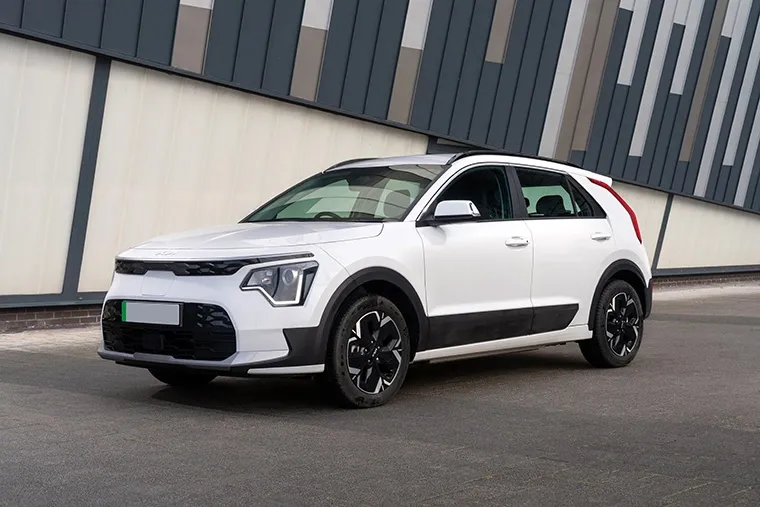 White Kia Niro EV parked in front of a modern building.
