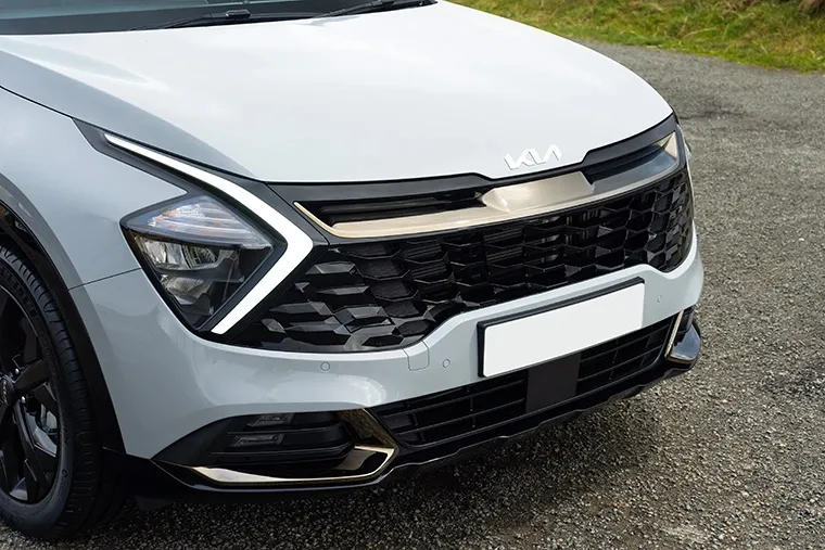 Close-up of the Kia Sportage front grille and LED headlights, highlighting the bold new Kia logo and distinctive modern design.