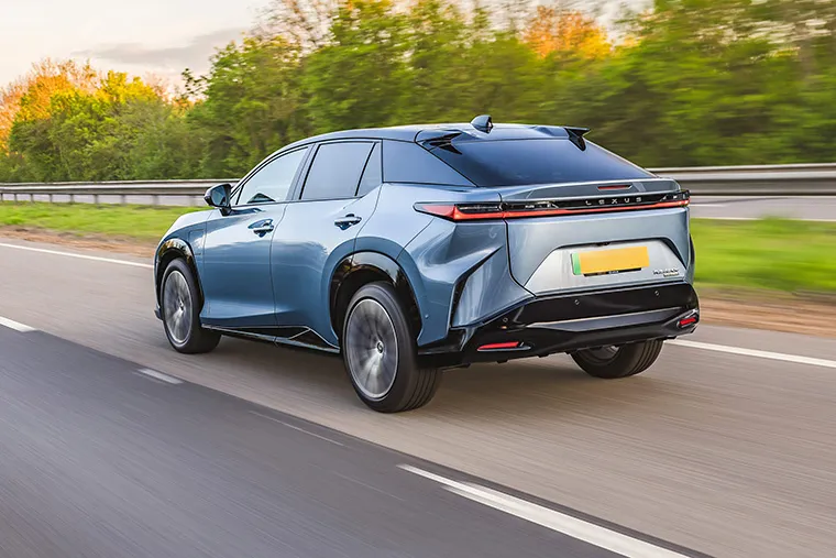 Rear view of a metallic blue Lexus RZ electric SUV driving on a motorway
