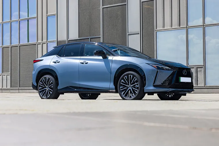 Side view of a Lexus RZ electric SUV in a modern urban setting, finished in metallic blue with black trim and stylish alloy wheels.