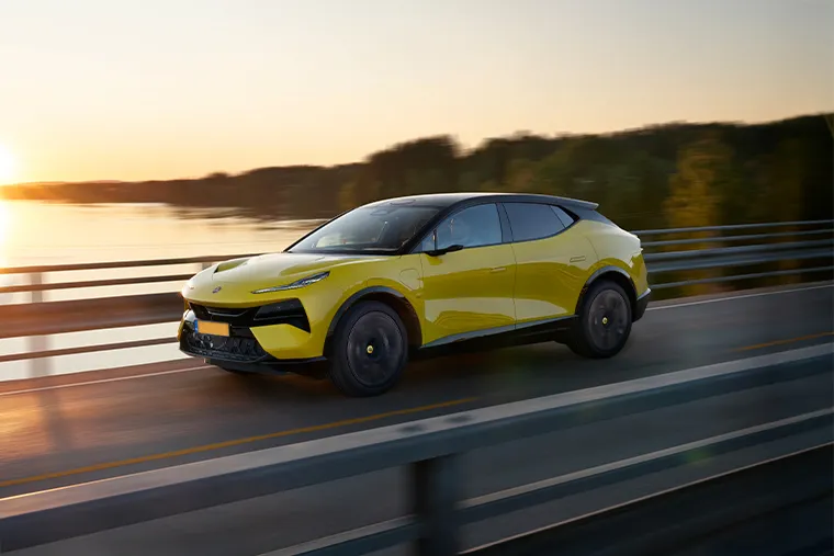 Lotus Eletre electric SUV in yellow driving on bridge at sunset