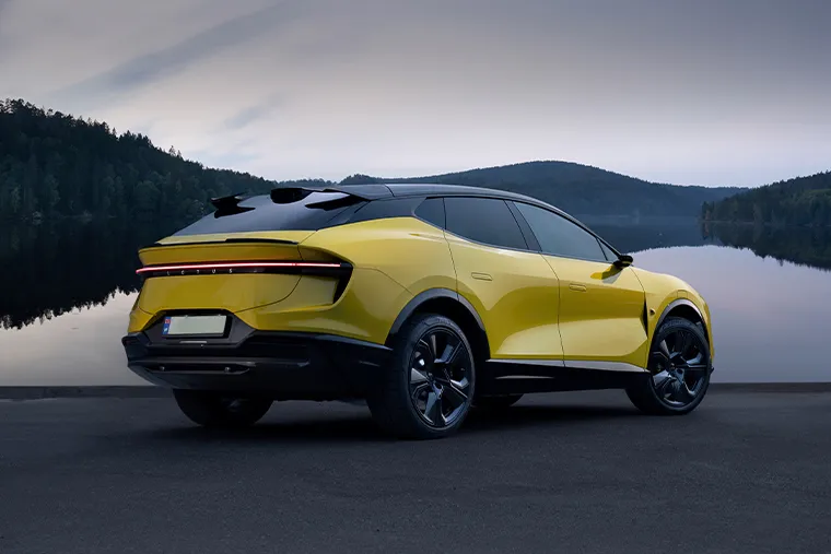 Yellow Lotus Eletre electric SUV rear three-quarter view parked by a lake with forested hills in the background