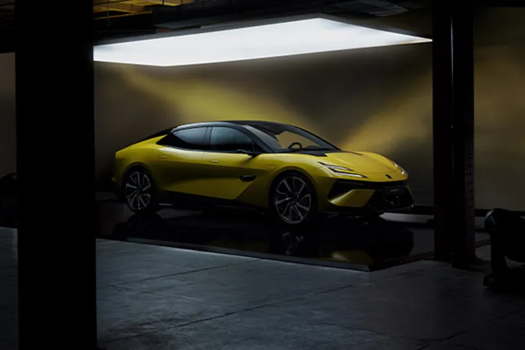 Yellow Lotus Emeya electric grand tourer in a dimly lit studio, side-front view