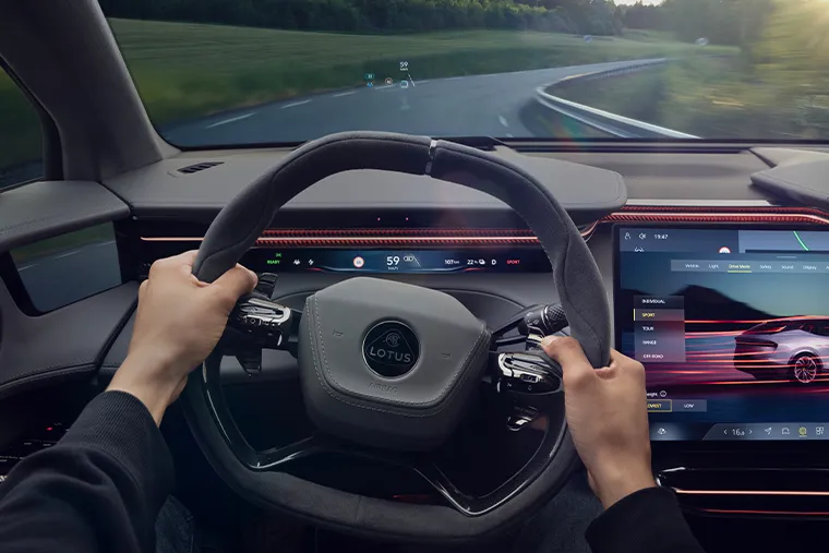 Lotus electric SUV interior with digital cockpit and driver holding steering wheel on the road