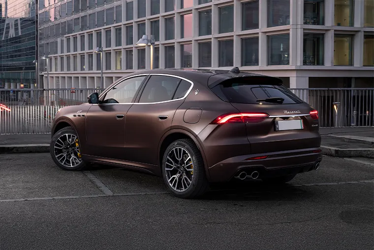 Brown Maserati Grecale SUV parked in modern city setting, rear three-quarter view