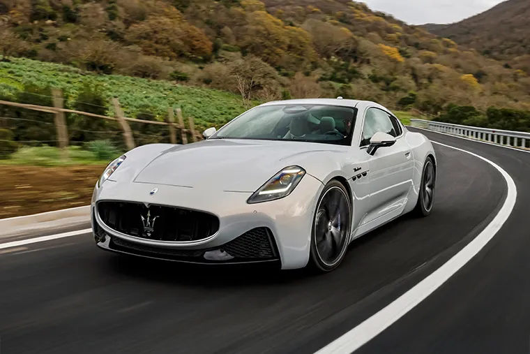 White Maserati GranTurismo sports car driving on a mountain road