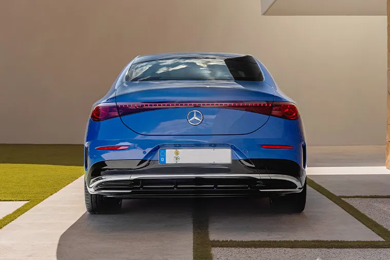 Rear view of blue Mercedes-Benz EQE electric saloon showing full-width LED tail light design