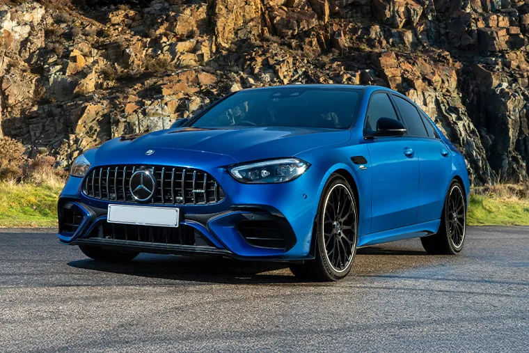 Blue Mercedes-AMG C63 sports saloon with Panamericana grille and black alloy wheels parked in front of rocky backdrop