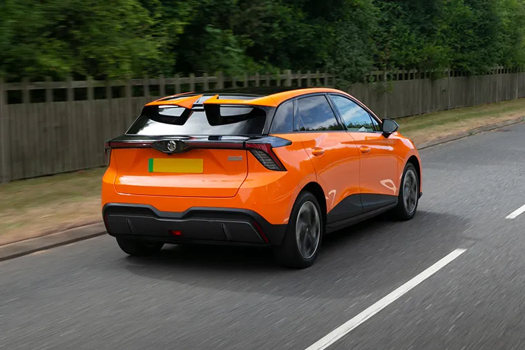 Orange MG4 EV electric hatchback driving on a UK road rear view