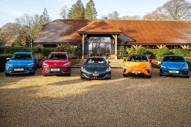 Line-up of MG cars including MG ZS EV, MG HS, parked outside a house