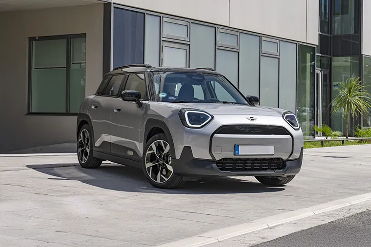 Silver MINI Countryman Electric parked in front of a modern office building.