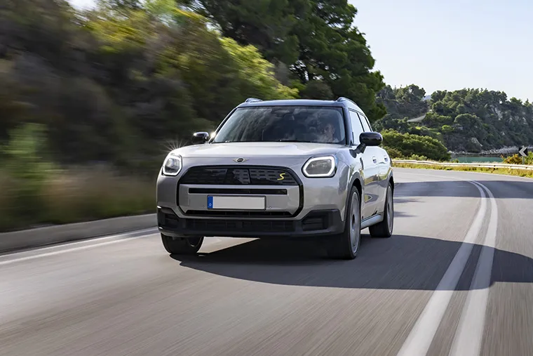 Silver MINI Countryman S Electric driving on a coastal road.