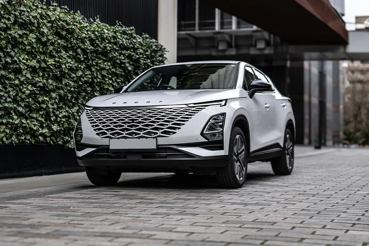 White SUV with a bold diamond-pattern grille parked on a modern city street beside a wall covered in green ivy.
